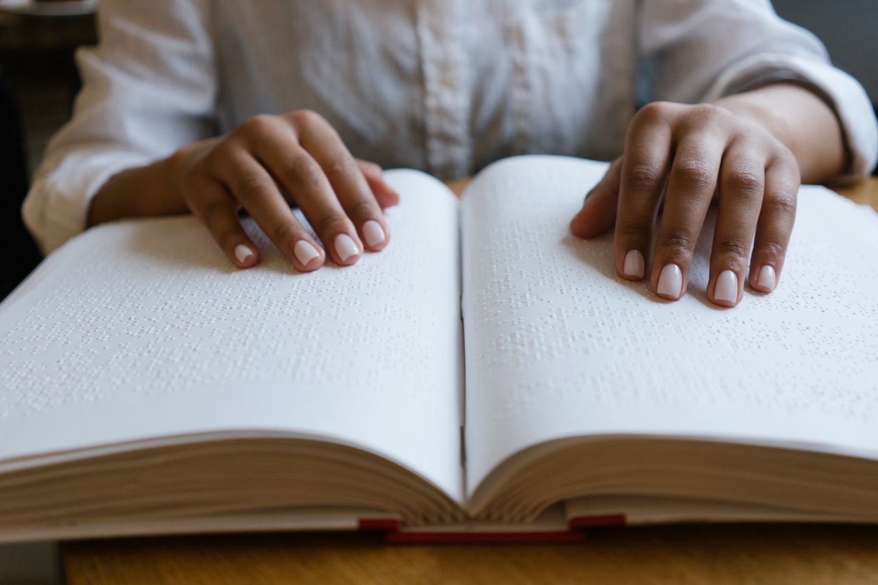 Hands reading a Braille book, emphasizing sensory perception and tactile learning.