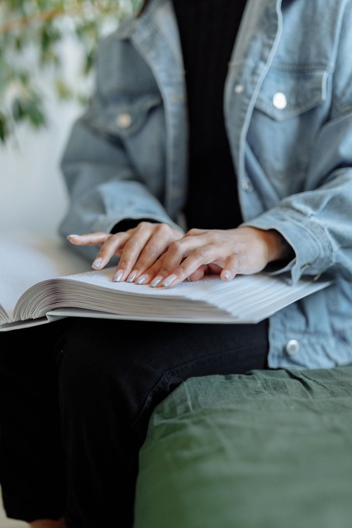 A close-up image of hands reading a Braille book, highlighting sensory perception.